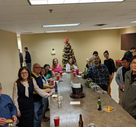 A Group Of People Standing Around A Table