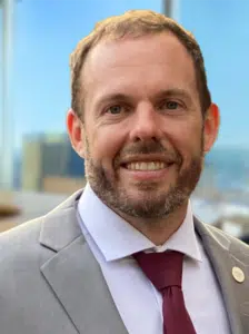 a man wearing a suit and tie smiling at the camera