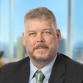 a man wearing a suit and tie smiling at the camera